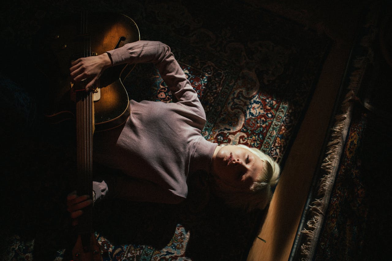 A Woman Lying Down While Playing the Guitar